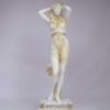 The Statue of Aphrodite stands and holds her head with both her hands in Patina color