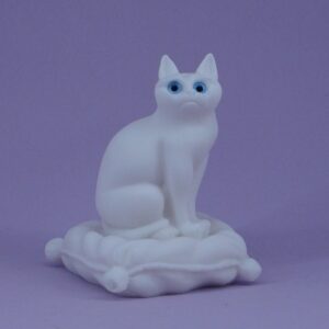 The statue of a cat sitting on a pillow in White color
