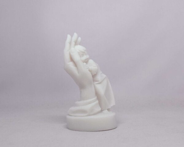 The statue of a boy is held by a hand in White color